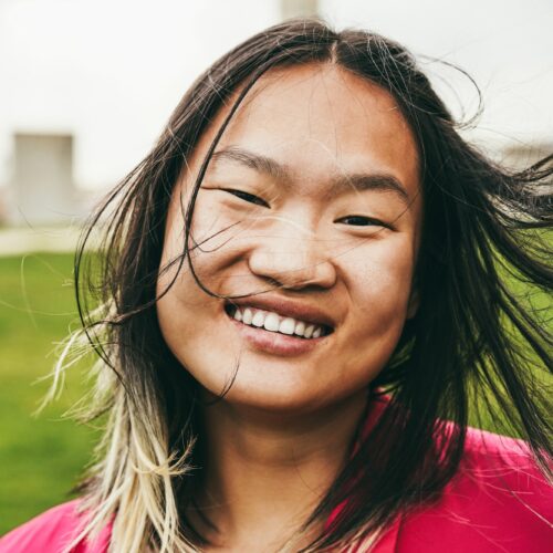 Asian girl smiling on camera at city park - Focus on face