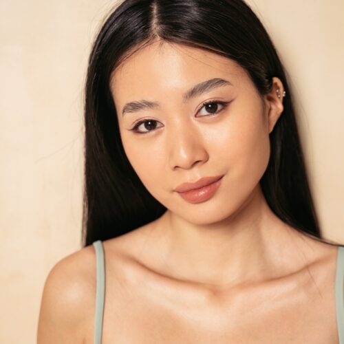 Portrait of asian korean woman with beautiful face looking at camera near wall